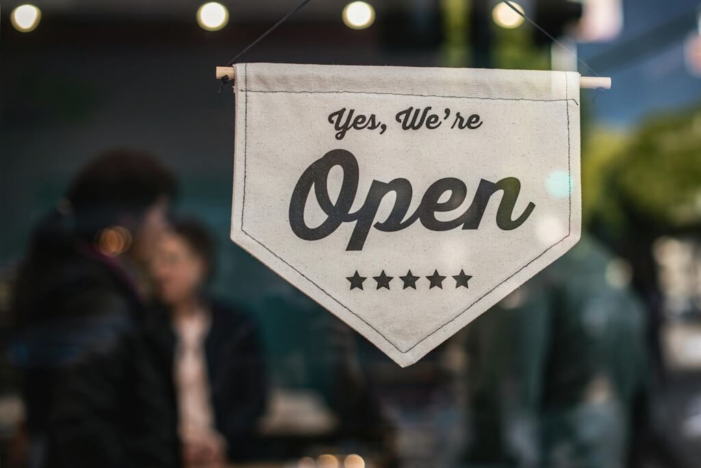 A welcoming "Yes, We're Open" sign hanging in a window, signaling business availability and inviting customers inside.