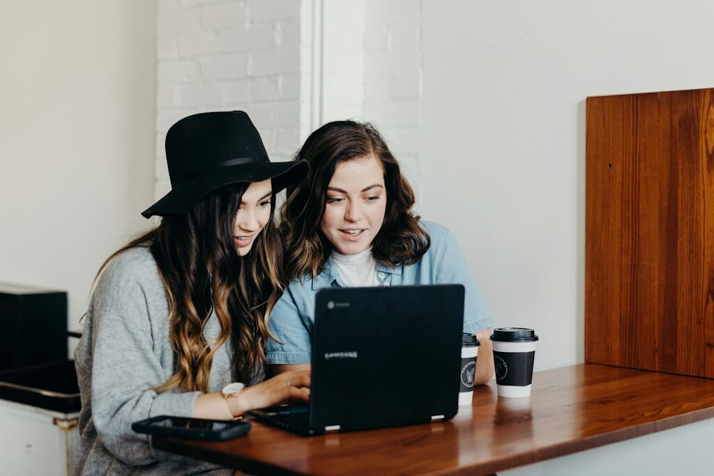 Two friends on a laptop in a coffee shop